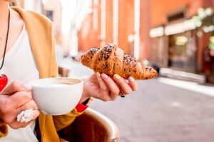 Woman having italian breakfast of coffee and pastry in Bologna