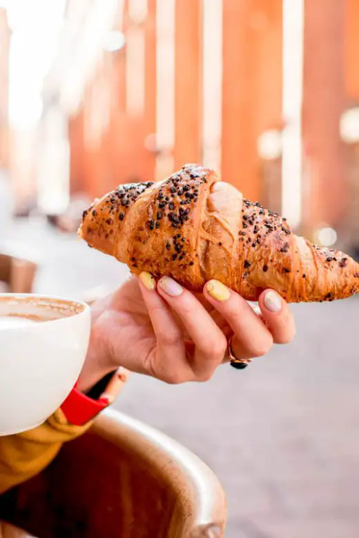 Woman having italian breakfast of coffee and pastry in Bologna