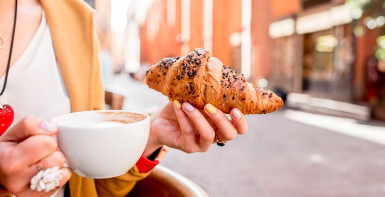 Woman having italian breakfast of coffee and pastry in Bologna