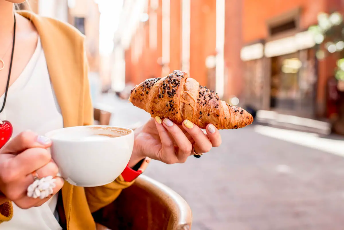 Woman having italian breakfast of coffee and pastry in Bologna
