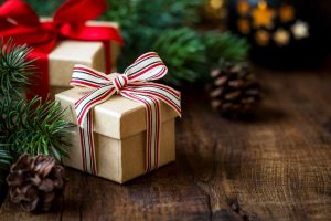 Wrapped Christmas gifts on dark rustic wooden table with pine cones and fir branches