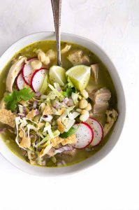 Pozole verde, a traditional Mexican soup made with hominy, pork, chicken, and a verde sauce made from tomatillos and green chiles.