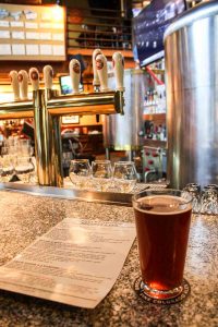 A beer and menu on the bar with tap handles in the background at the original Breckenridge Brewery & Pub in Breckenridge, Colorado, USA