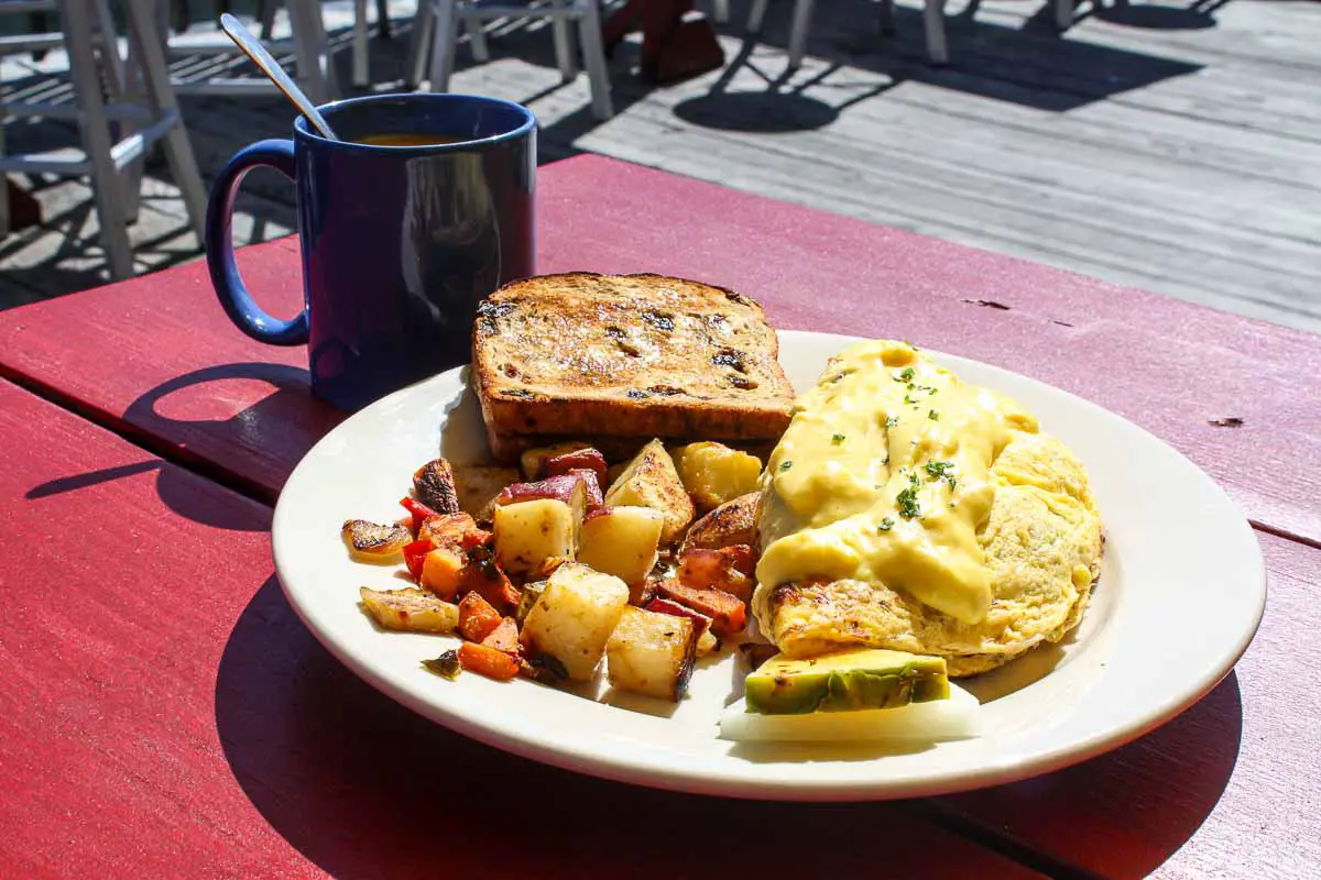 Breakfast of a Casco Bay Omelette filled with Maine lobster and crab meat with home fries and cinnamon raisin toast with a cup of coffee on the deck at The Porthole restaurant in Portland, Maine, USA
