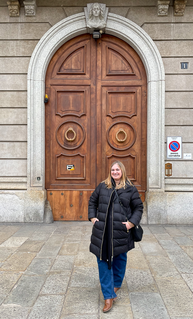 Female traveler in front of a decorative door in Milan